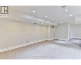 A spacious room with a light-colored floor and walls, and a door on the right side.