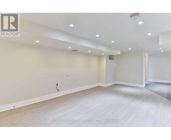 A spacious room with a light-colored floor and walls, and a door on the right side.