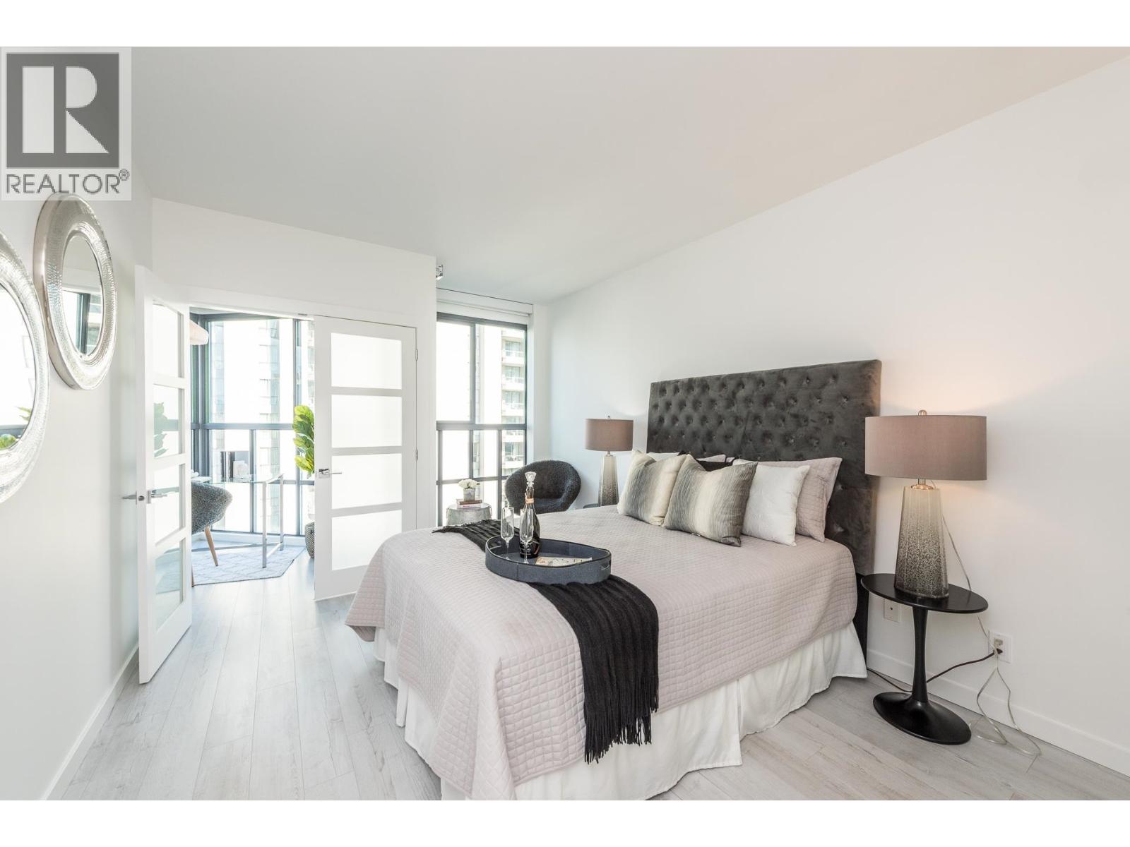 A bedroom with a large bed and a lamp on a side table.