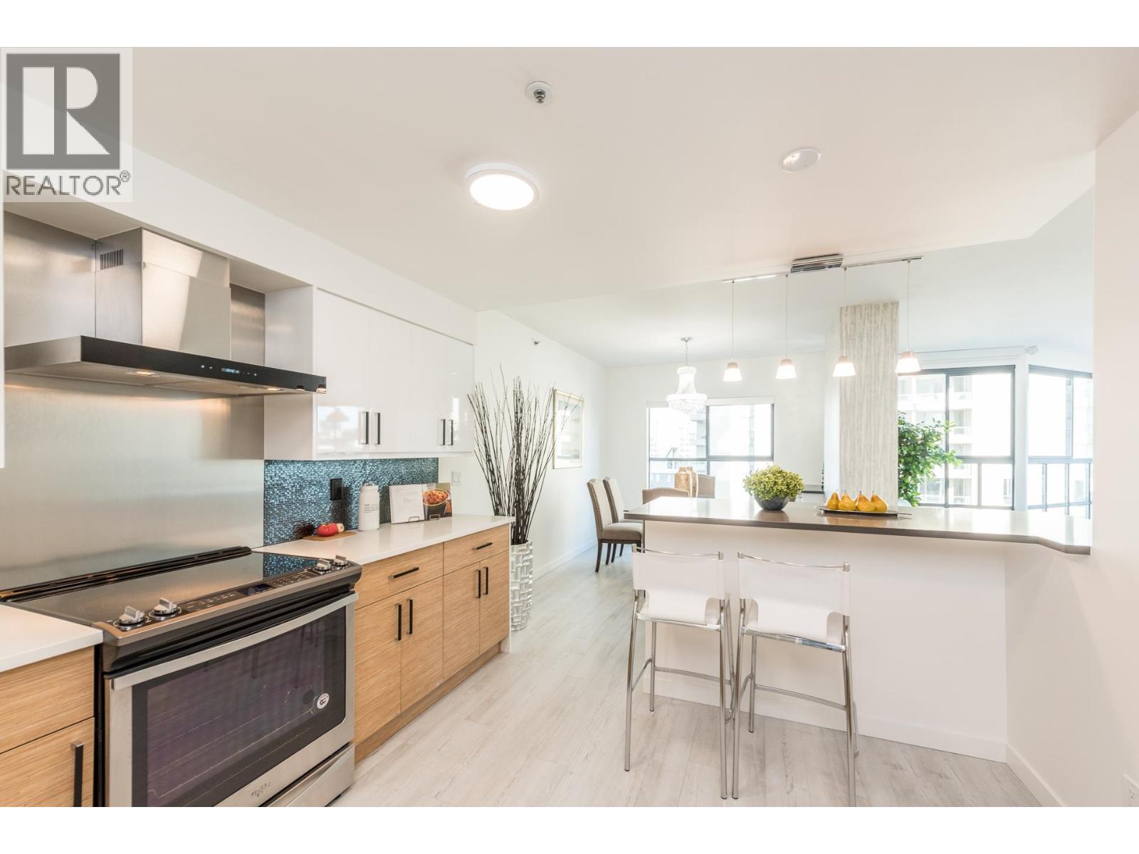 A modern kitchen with a stove top oven and a breakfast bar.