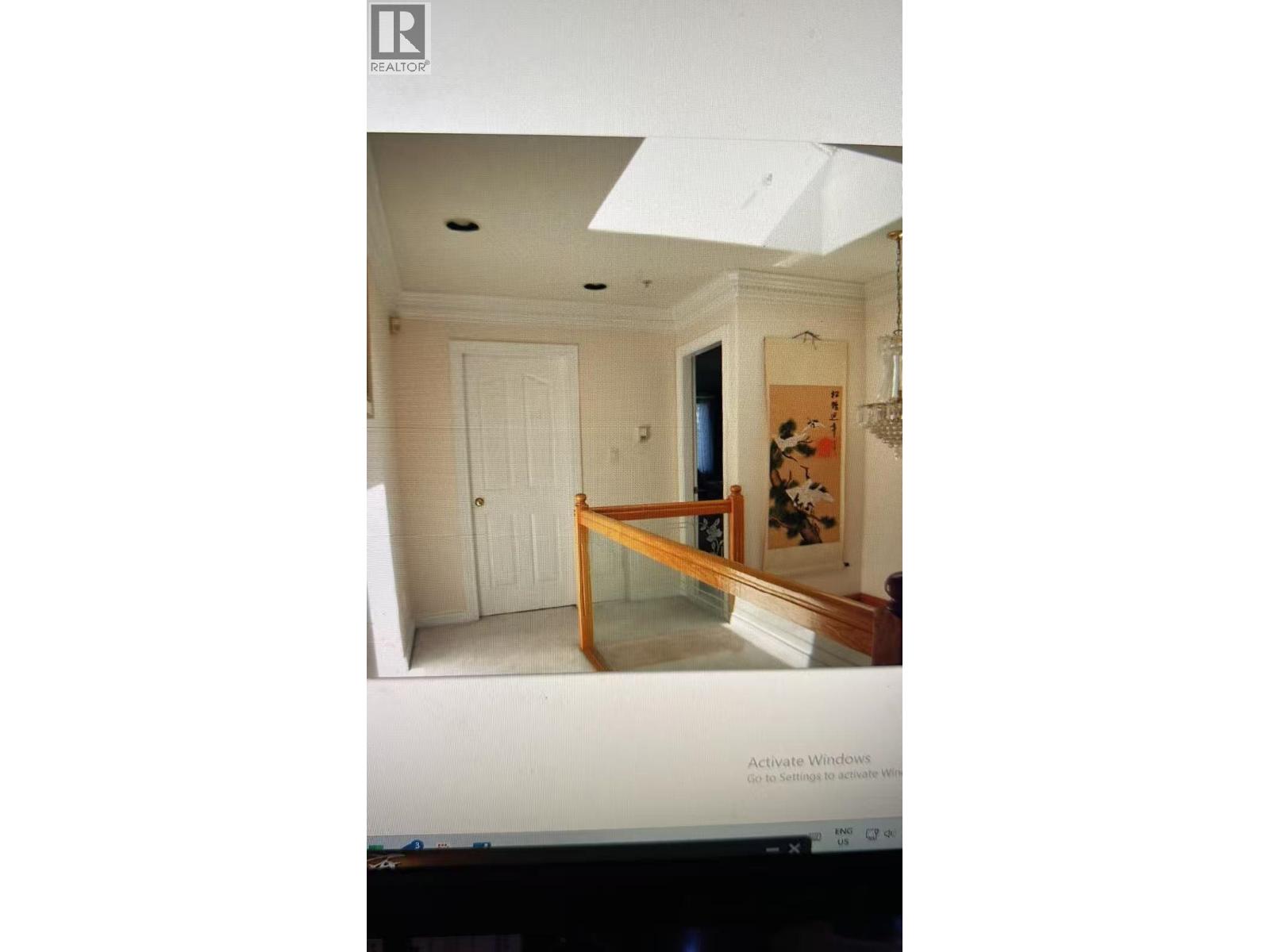 A computer screen shows a room with a door and a painting on the wall.