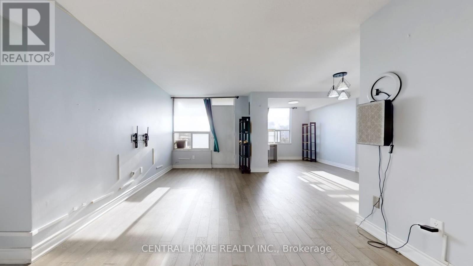 A spacious room with a large window and a wooden floor.
