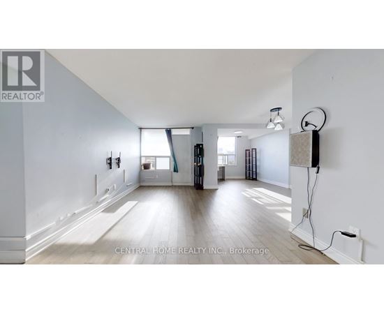 A spacious room with a large window and a wooden floor.