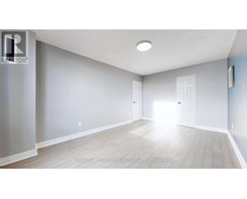A spacious room with light wood flooring and white walls.
