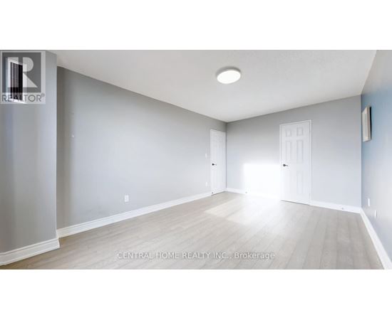 A spacious room with light wood flooring and white walls.