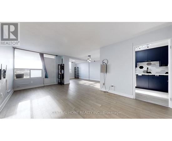 A spacious room with a large window and a kitchen area with a sink and stove.