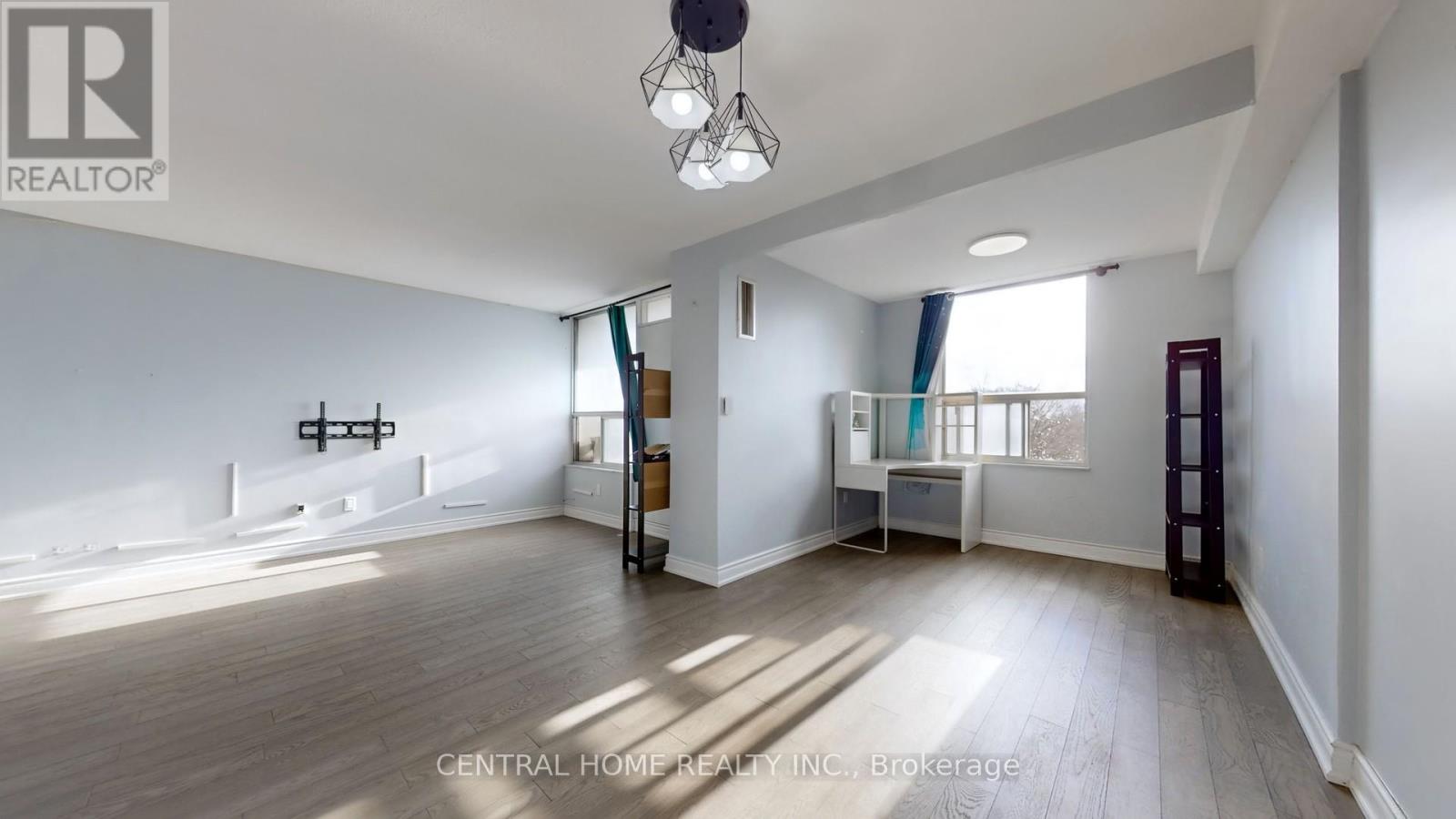 A spacious living room with a large window and a wooden floor.