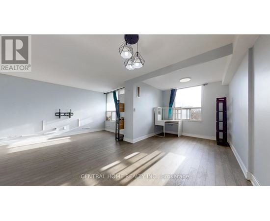 A spacious living room with a large window and a wooden floor.