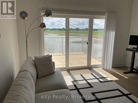 A living room with a grey couch and a large window with a view of a lake.