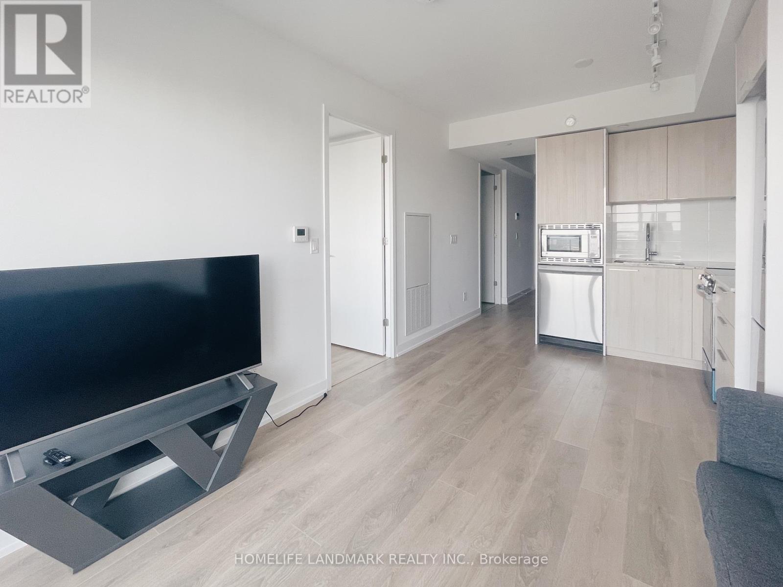 A modern living room with a flat screen TV and a grey sofa.