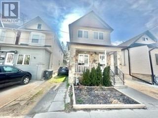 A house with a car parked in front and a garden bed in the front yard.