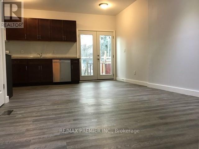 A spacious room with wooden flooring and a sliding glass door leading to a balcony.
