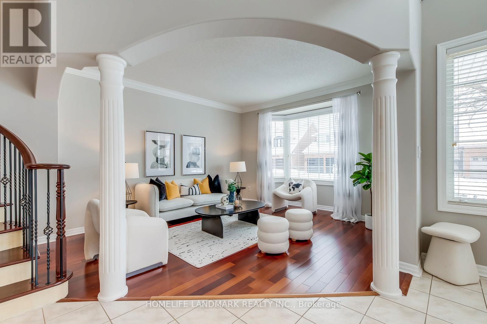 A living room with a staircase on the left and a couch with pillows in the center.