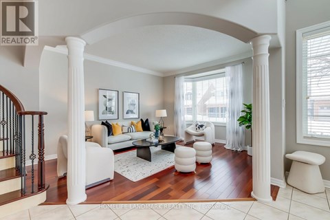 A living room with a staircase on the left and a couch with pillows in the center.