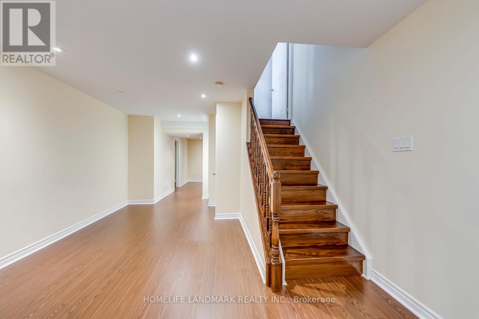 A spacious hallway with wooden stairs leading to another room.
