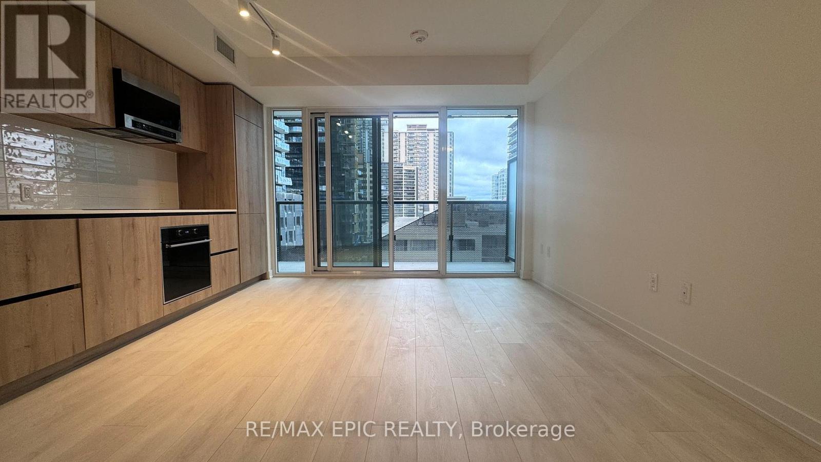 A spacious room with wooden flooring and a large window overlooking a cityscape.