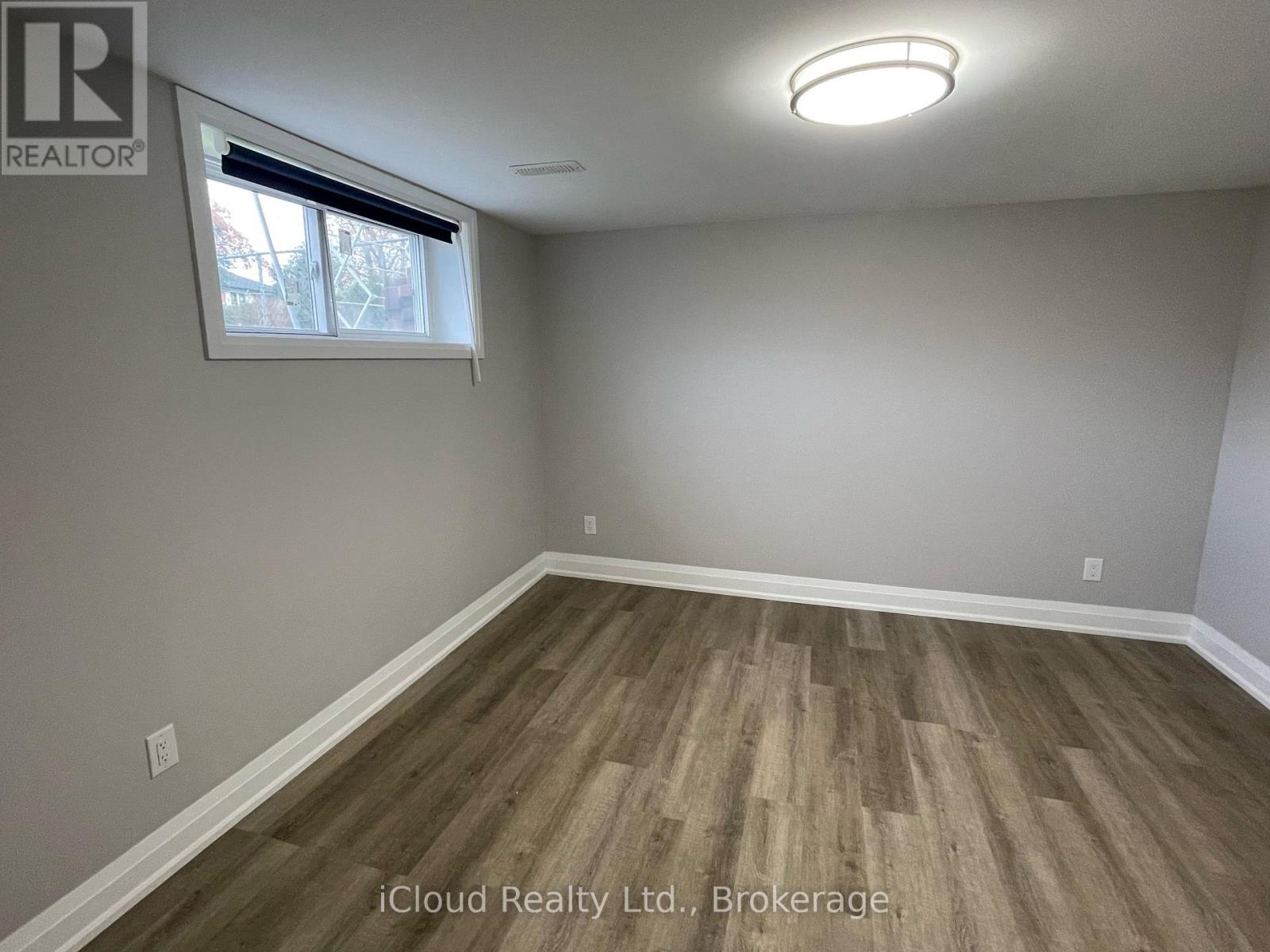A room with wooden flooring and a window with blinds.