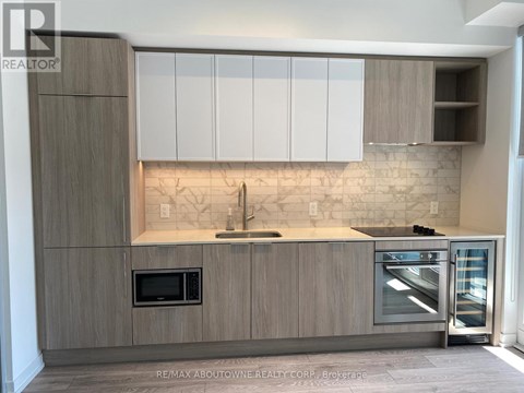 A modern kitchen with wooden cabinets and a marble backsplash.