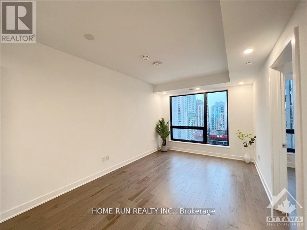 A spacious room with a large window and wooden flooring.