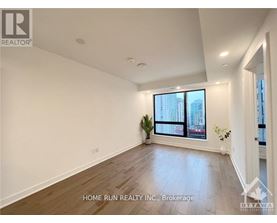 A spacious room with a large window and wooden flooring.