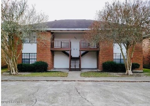 A two-story brick building with a balcony on the second floor.
