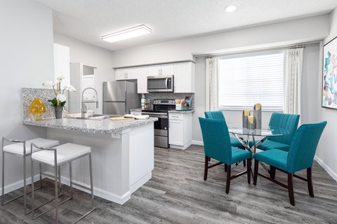 A kitchen with a bar area and a dining table with chairs.