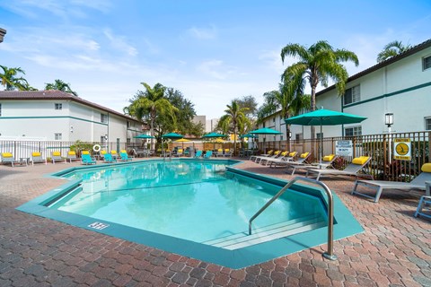 A swimming pool surrounded by lounge chairs and umbrellas.