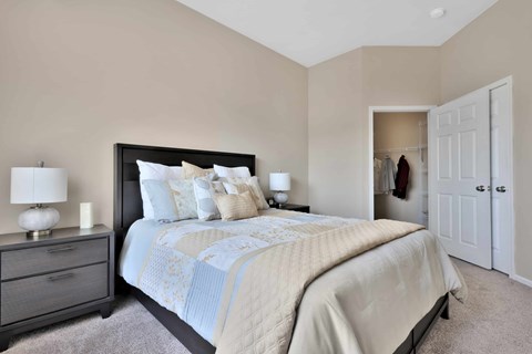 A bedroom with a large bed and a nightstand with a lamp.