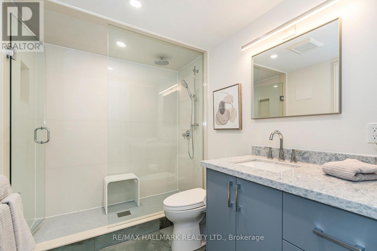 A bathroom with a glass shower stall and a toilet.