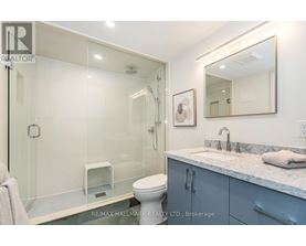 A bathroom with a glass shower stall and a toilet.