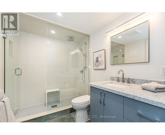 A bathroom with a glass shower stall and a toilet.