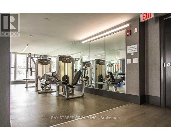 A gym with a mirrored wall and a sign that says exit.