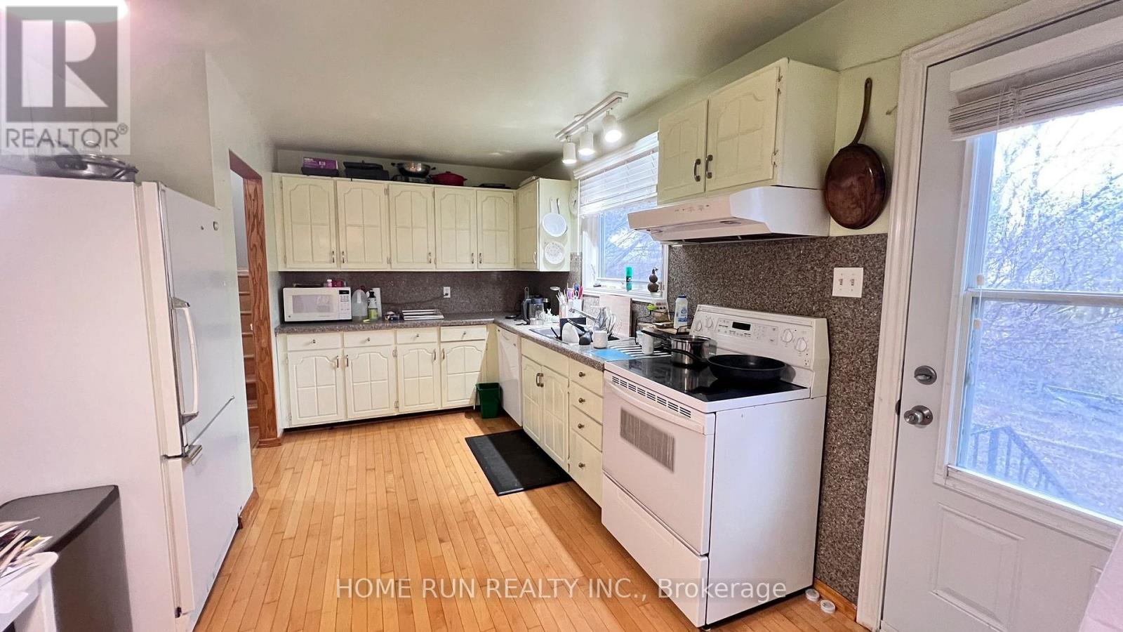 A kitchen with white appliances and wooden floors.