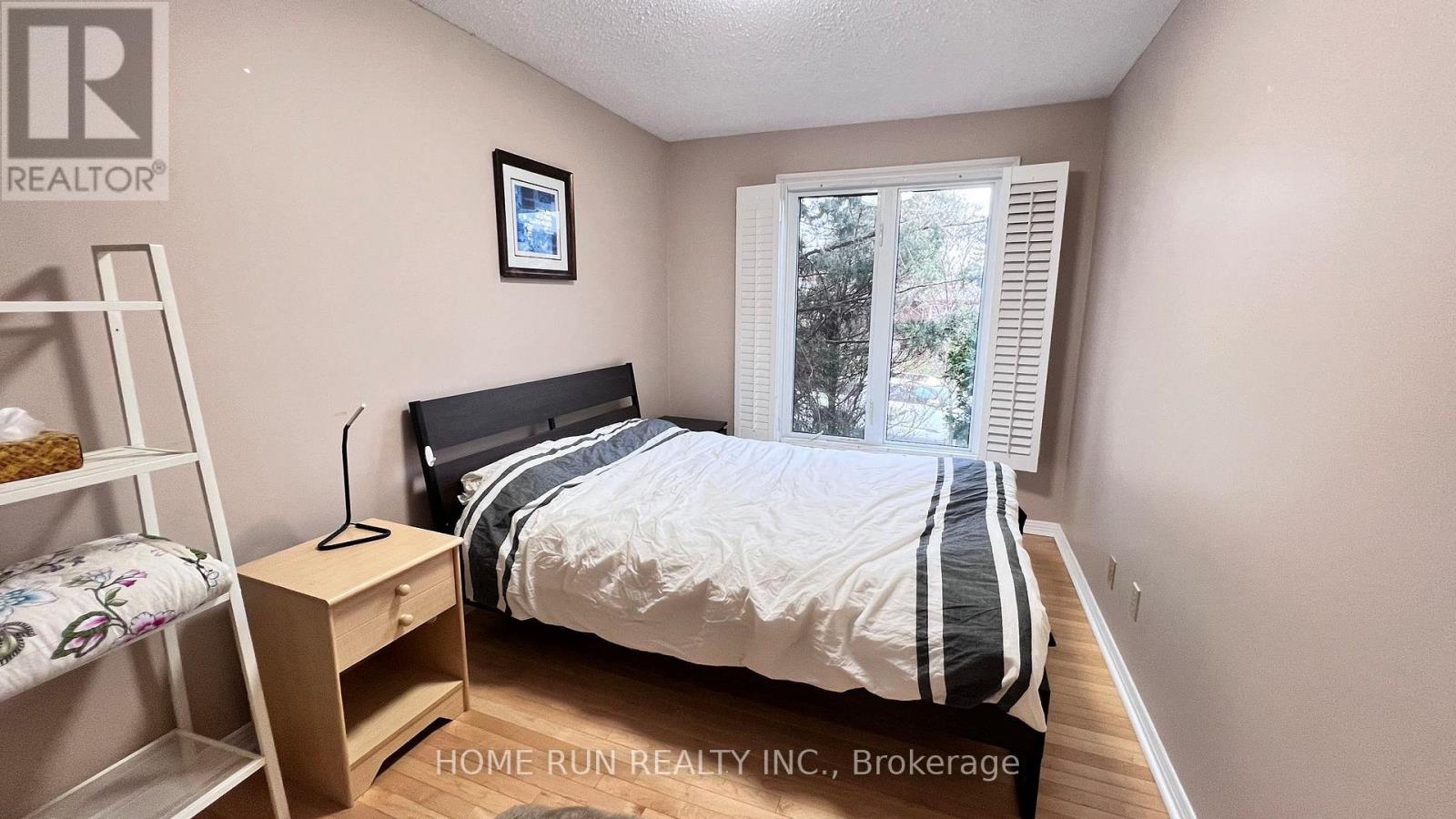 A bedroom with a bed, nightstand, and a window with blinds.