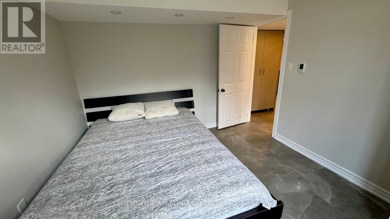 A bedroom with a bed, pillows, and a door.