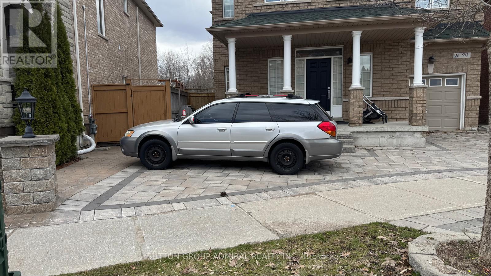 A silver minivan is parked in a driveway.