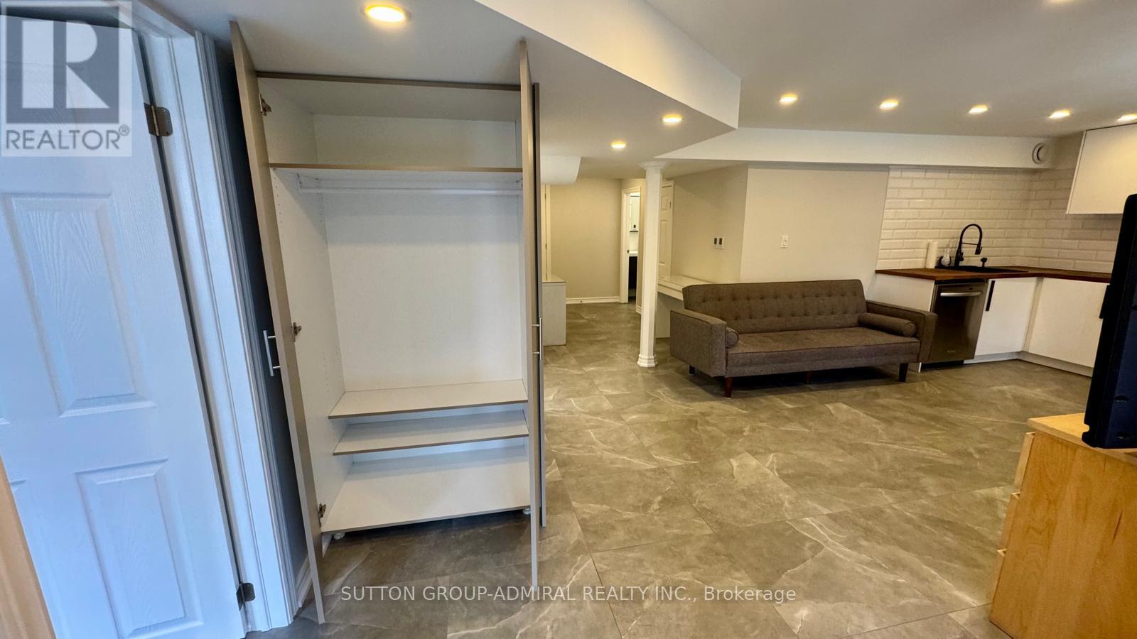 A living room with a couch, a television, and a kitchen area with an open fridge.