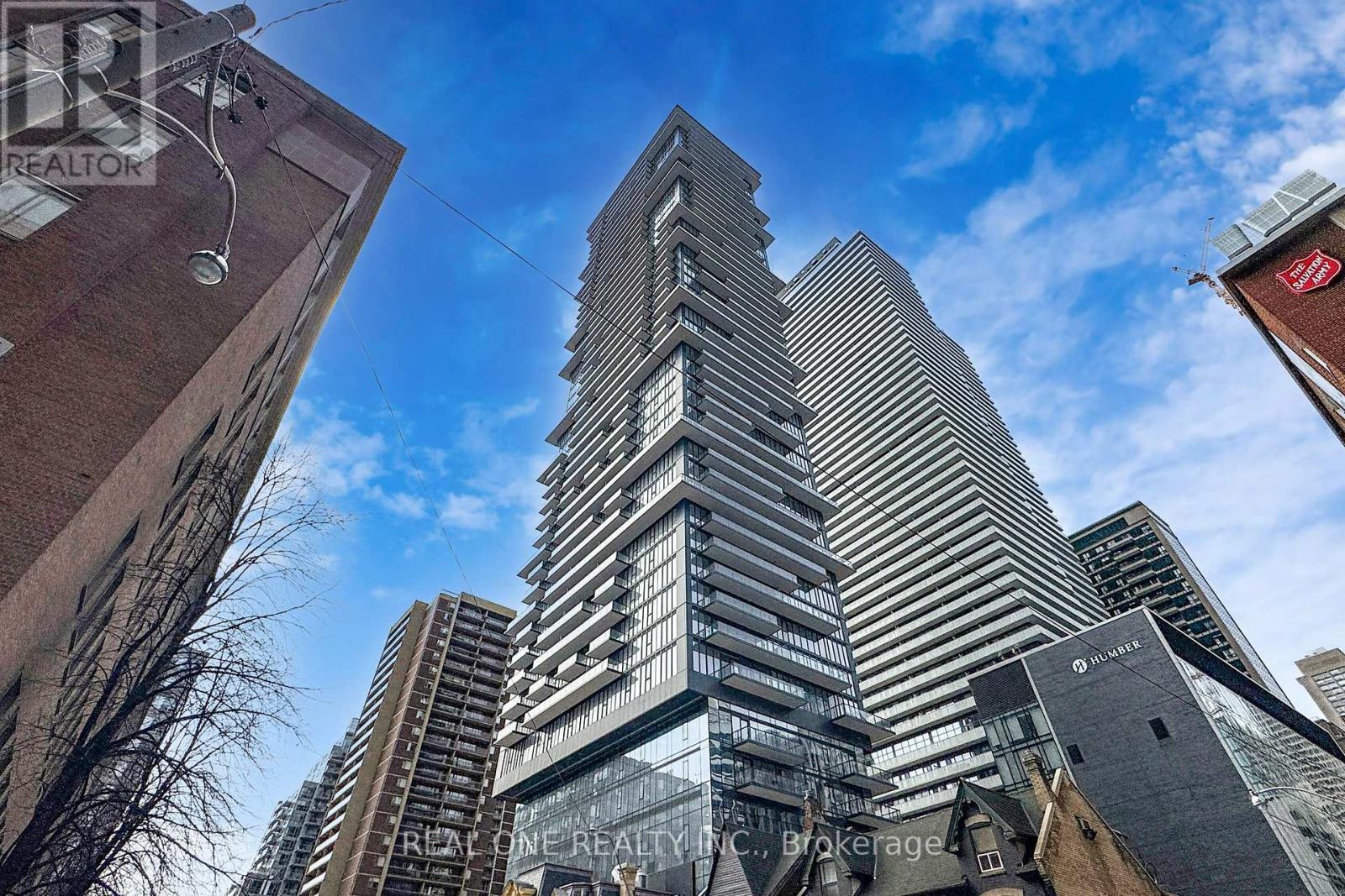 A tall building with a glass facade stands in the middle of a cityscape.