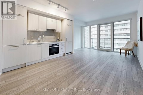 A modern kitchen with white cabinets and a wooden floor.