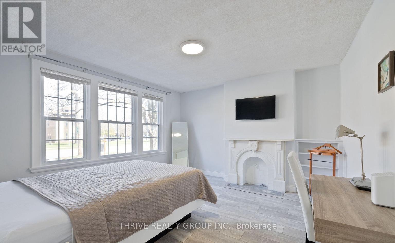 A bedroom with a bed, fireplace, and a television.