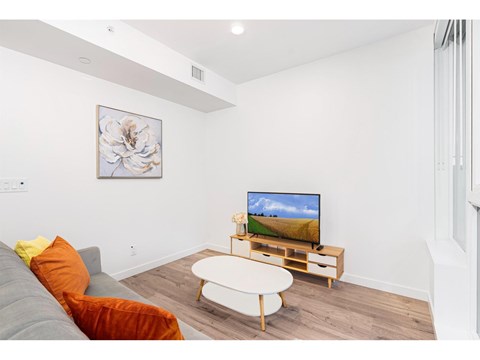 A living room with a grey couch, a white coffee table, and a television on a wooden stand.