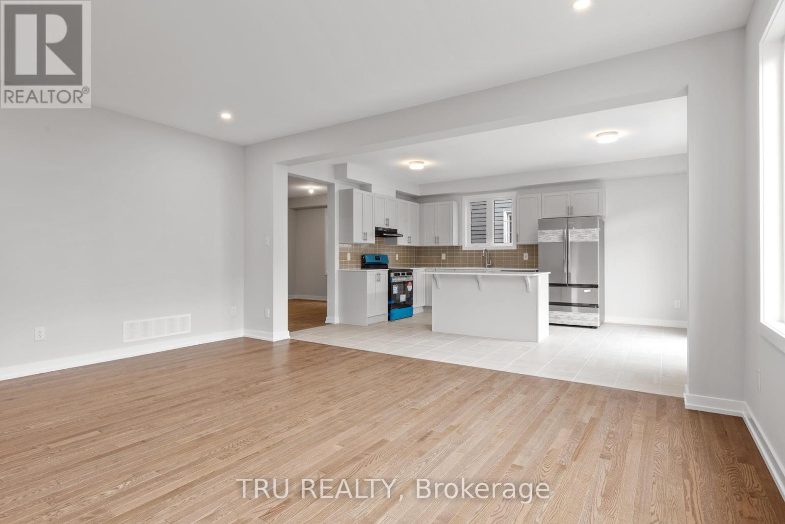A spacious, empty room with wooden flooring and white walls.