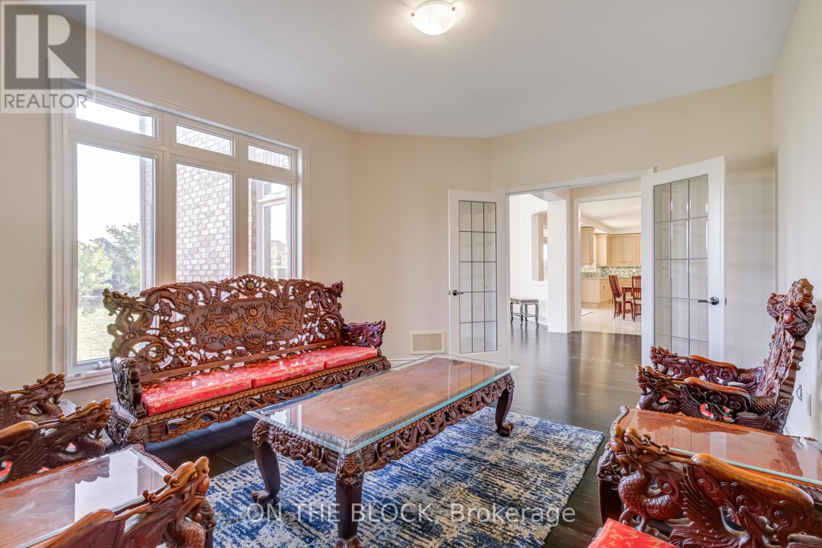 A living room with a red sofa and wooden chairs.