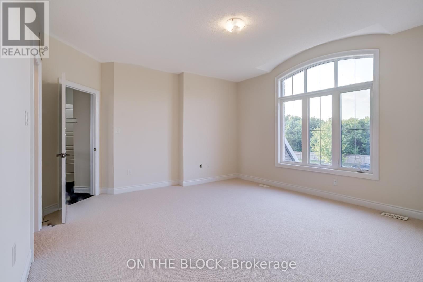 A spacious room with a large window and a door leading to another room.
