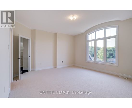 A spacious room with a large window and a door leading to another room.