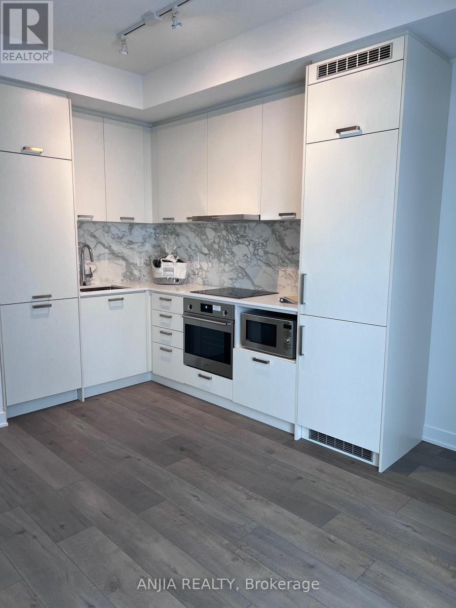 A kitchen with white cabinets and a marble backsplash.