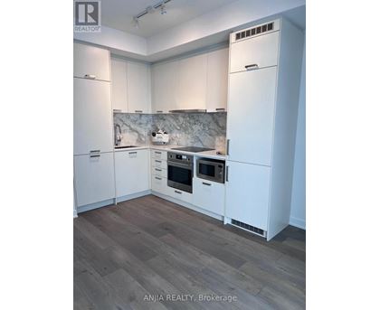 A kitchen with white cabinets and a marble backsplash.