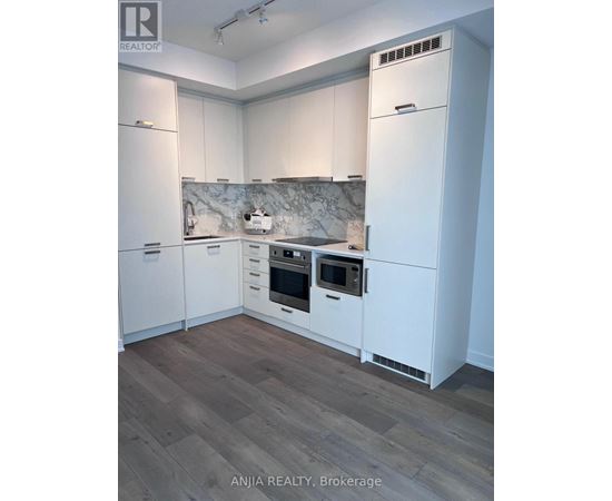 A kitchen with white cabinets and a marble backsplash.