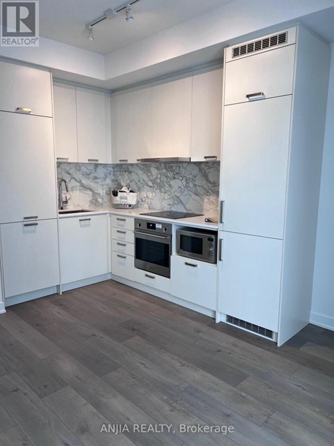 A kitchen with white cabinets and a marble backsplash.
