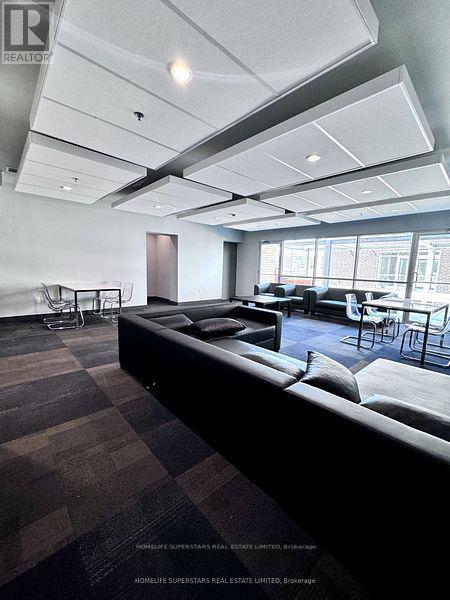 A spacious room with a long black couch and a table with chairs.